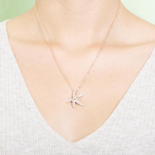 The picture shows a model wearing a 925 sterling silver, rose gold plated, dancing starfish pendant with topaz.