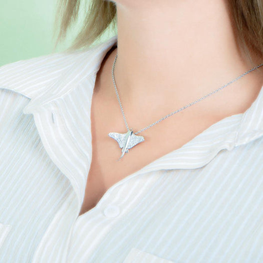 The picture shows a model wearing a 925 sterling silver, white gold plated, pavé eagle ray pendant with cubic zirconia.