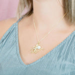 The picture shows a model wearing a 925 sterling silver, yellow gold vermeil, pavé octopus pendant with topaz.