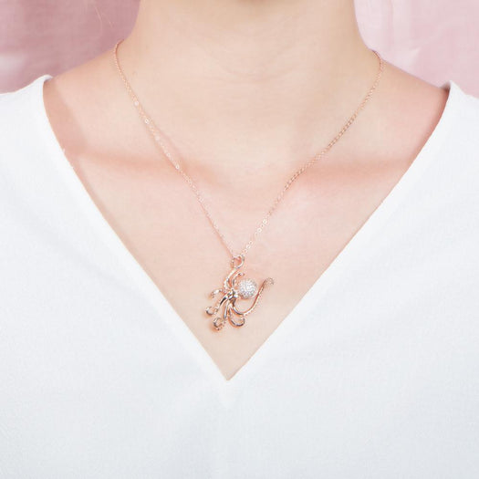 The picture shows a model wearing a 925 sterling silver, rose gold vermeil, pavé octopus pendant with topaz.