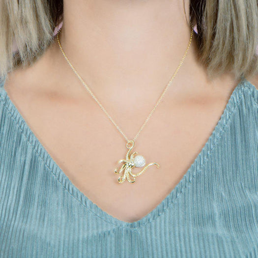 The picture shows a model wearing a 925 sterling silver, yellow gold vermeil, pavé octopus pendant with topaz.