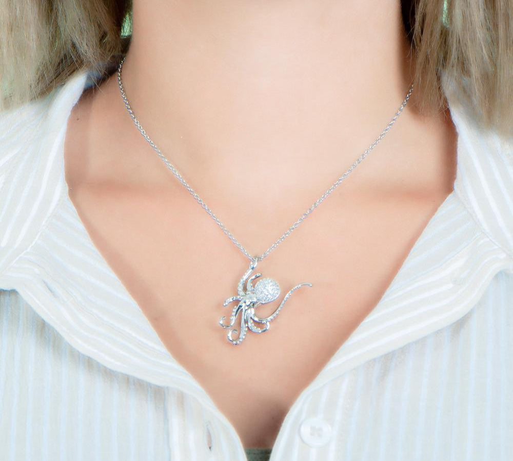 The picture shows a model wearing a 925 sterling silver, white gold vermeil, pavé octopus pendant with topaz.