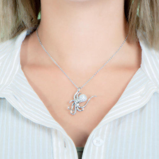 The picture shows a model wearing a 925 sterling silver, white gold vermeil, pavé octopus pendant with topaz.