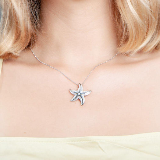 The picture shows a model wearing a 925 sterling silver, white gold vermeil, happy starfish pendant with topaz.