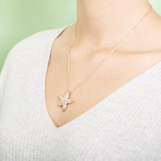 The picture shows a model wearing a 925 sterling silver, rose gold vermeil, happy starfish pendant with topaz.