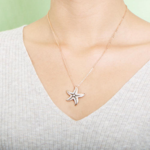 The picture shows a model wearing a 925 sterling silver, rose gold vermeil, happy starfish pendant with topaz.