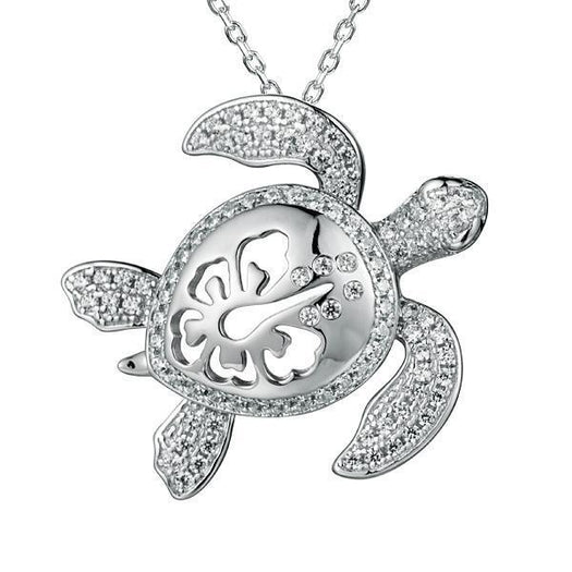 The photo shows a white gold pavé hibiscus adorned sea turtle pendant.