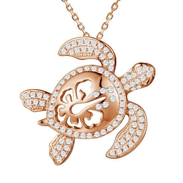 The photo shows a rose gold pavé hibiscus adorned sea turtle pendant.