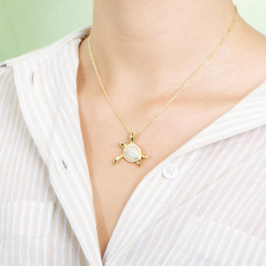 The picture shows a model wearing a 925 sterling silver, yellow gold vermeil, sea turtle pendant with topaz.