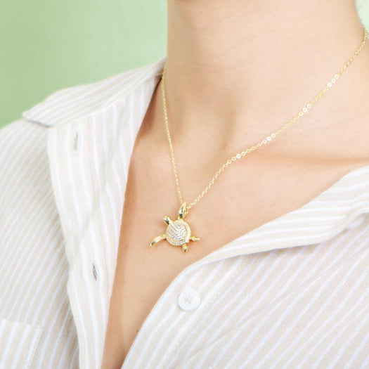 The picture shows a model wearing a 925 sterling silver, yellow gold vermeil, sea turtle pendant with topaz.