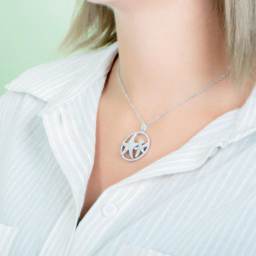 The picture shows a model wearing a 925 sterling silver, white gold vermeil, double starfish circle pendant with topaz.