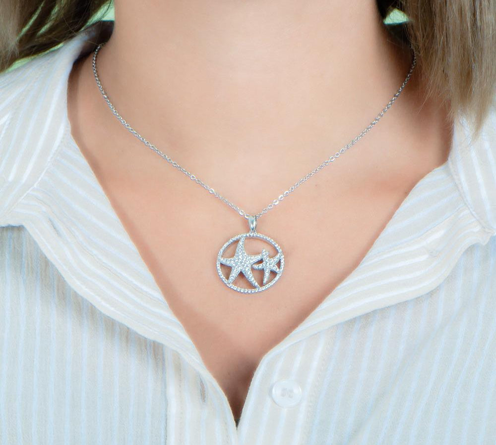 The picture shows a model wearing a 925 sterling silver, white gold vermeil, double starfish circle pendant with topaz.