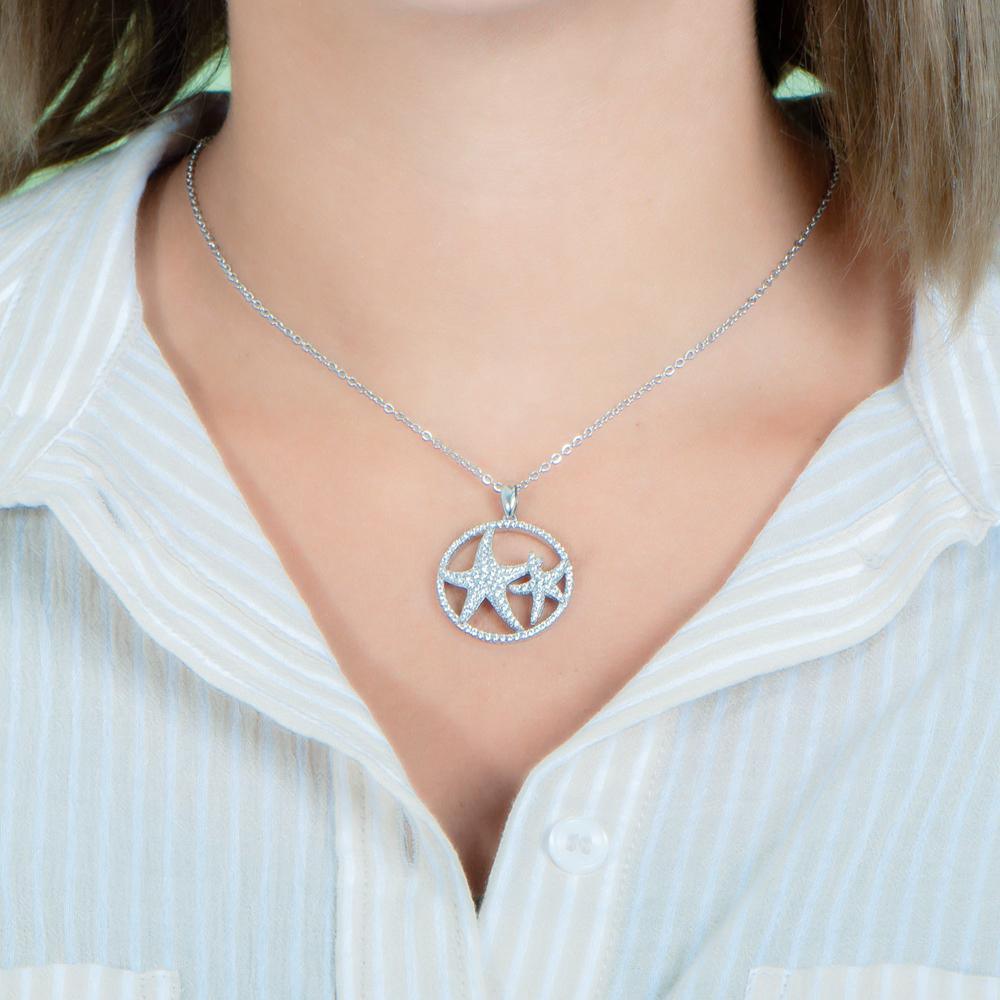 The picture shows a model wearing a 925 sterling silver, white gold vermeil, double starfish circle pendant with topaz.