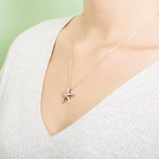 The picture shows a model wearing a 925 sterling silver, rose gold vermeil, starfish pendant with topaz.