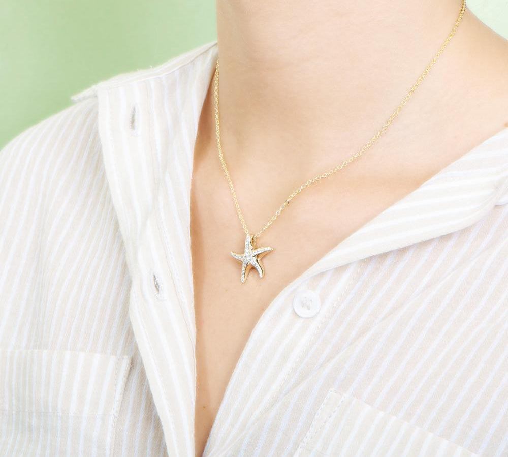The picture shows a model wearing a 925 sterling silver, yellow gold vermeil, starfish pendant with topaz.