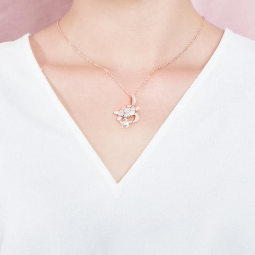 The picture shows a model wearing a 925 sterling silver, rose gold vermeil, double sea turtle pendant with topaz.