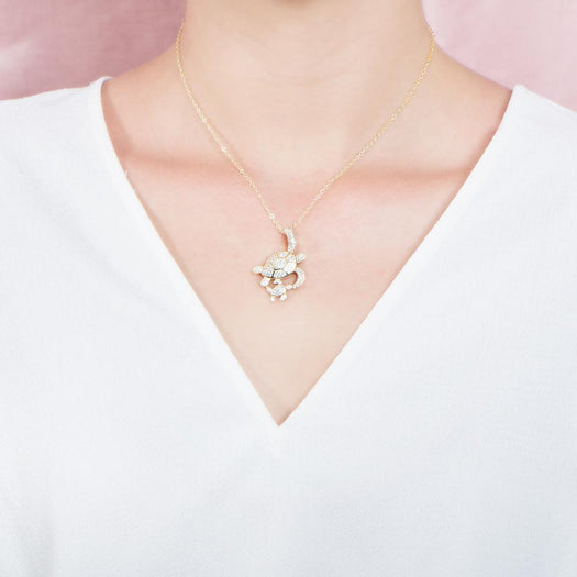 The picture shows a model wearing a 925 sterling silver, yellow gold vermeil, double sea turtle pendant with topaz.