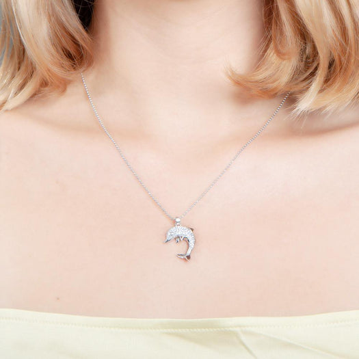 The picture shows a model wearing a 925 sterling silver, white gold-vermeil, dolphin pendant with cubic zirconia.