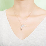 The picture shows a model wearing a 925 sterling silver, yellow gold-vermeil, dolphin pendant with topaz.