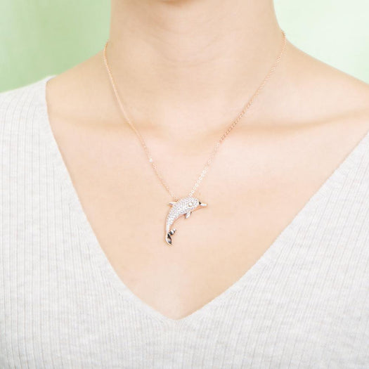 The picture shows a model wearing a 925 sterling silver, yellow gold-vermeil, dolphin pendant with topaz.
