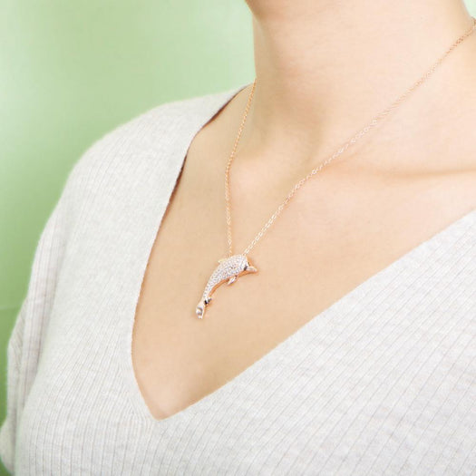The picture shows a model wearing a 925 sterling silver, rose gold-vermeil, dolphin pendant with topaz.