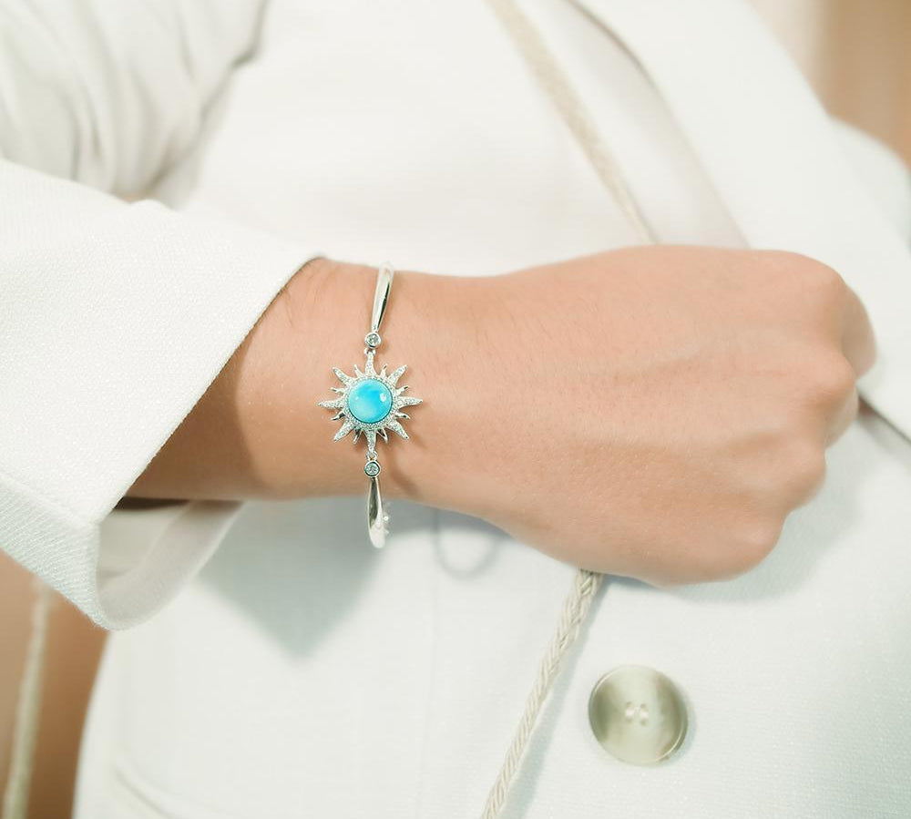 In this photo there is a model wearing a 925 sterling silver sun bracelet with blue larimar, topaz, and aquamarine gemstones.