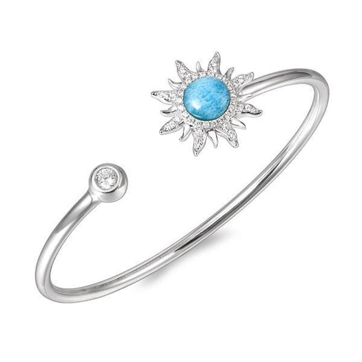 In this photo there is a sterling silver sun bangle with blue larimar, topaz, and aquamarine gemstones.