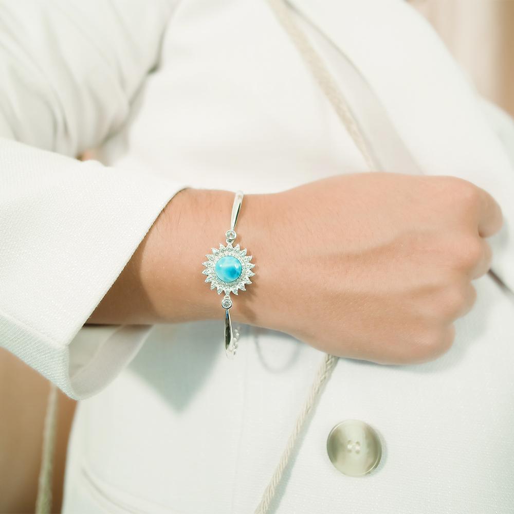 This picture shows a model wearing a 925 sterling silver sunflower bracelet with one blue larimar gemstone and topaz.