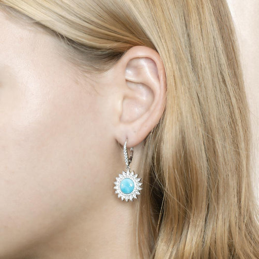 In this photo is a model with blonde hair in profile, wearing sterling silver sunflower dangle earrings with blue larimar and topaz gemstones.