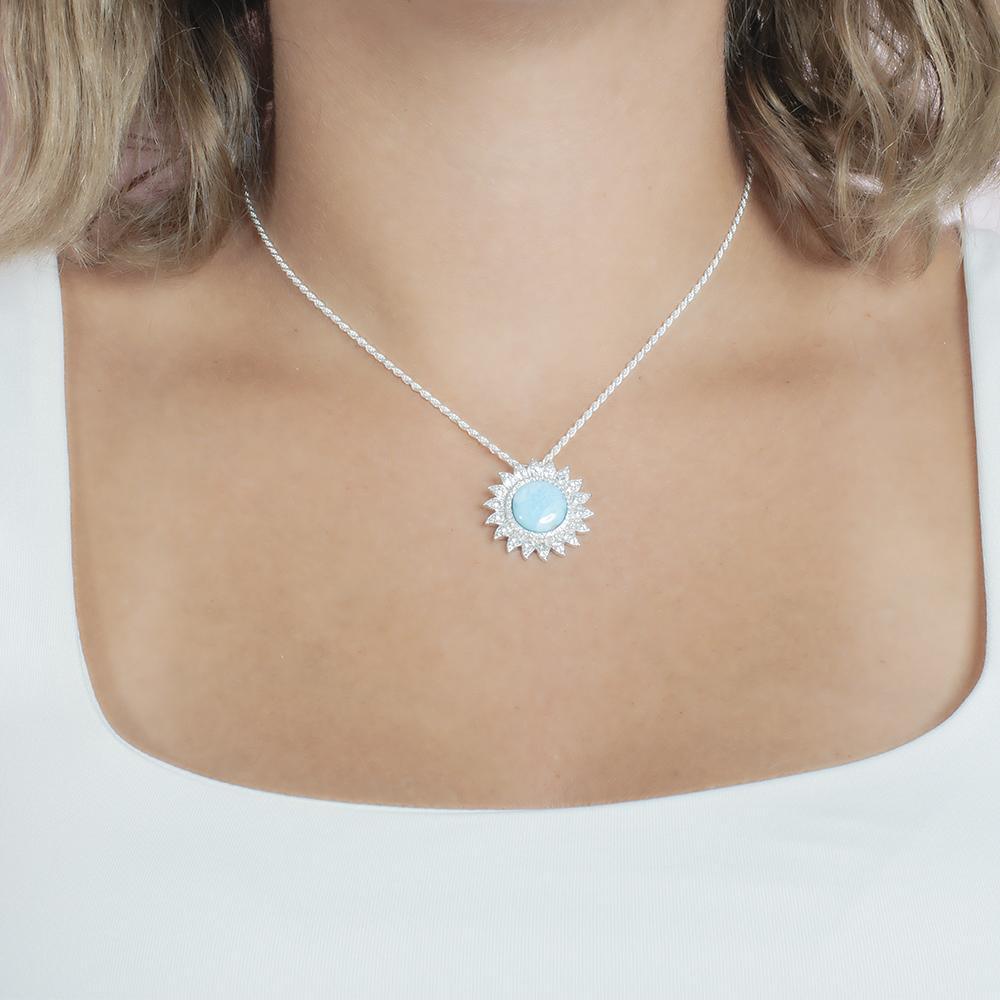 In this photo there is a model with blonde hair and a white shirt, wearing a sterling silver sunflower pendant with topaz and one blue larimar gemstone.