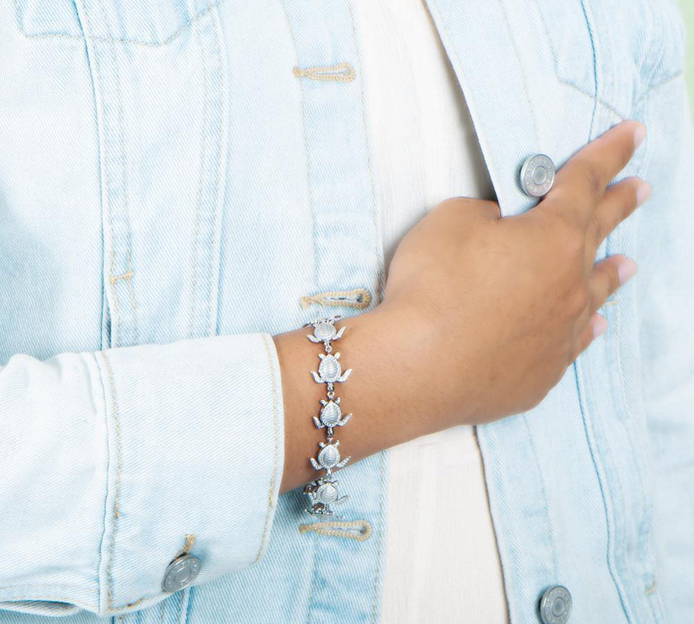 The picture shows a model wearing a 925 sterling silver white gold-plated sea turtle bracelet with cubic zirconia.