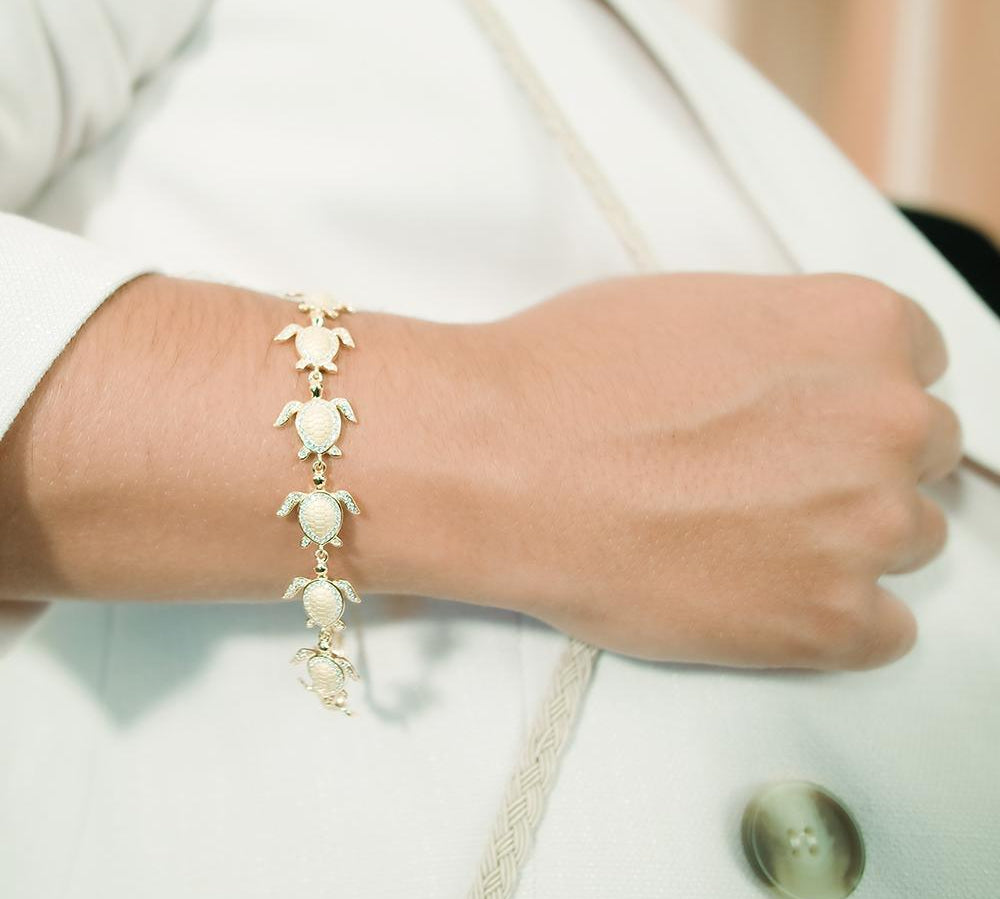 The picture shows a model wearing a 925 sterling silver yellow gold-plated sea turtle bracelet with cubic zirconia.