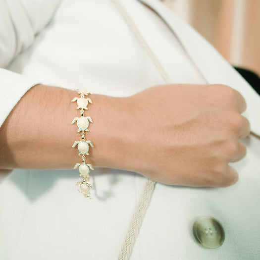 The picture shows a model wearing a 925 sterling silver yellow gold-plated sea turtle bracelet with cubic zirconia.