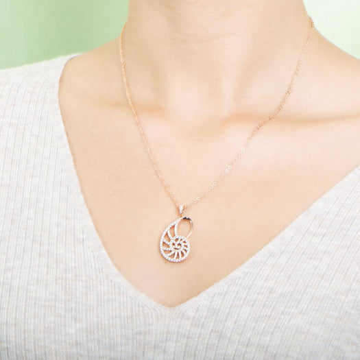 The picture shows a model wearing a 925 sterling silver pavé rose gold vermeil nautilus shell pendant with topaz.