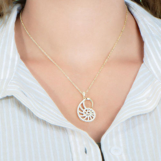 The picture shows a model wearing a 925 sterling silver pavé yellow gold vermeil nautilus shell pendant with topaz.