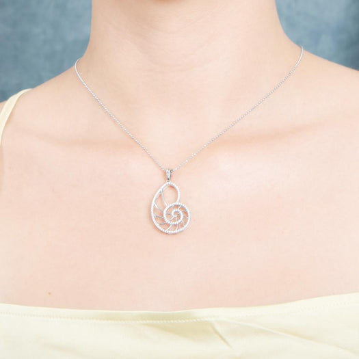 The picture shows a model wearing a 925 sterling silver pavé white gold vermeil nautilus shell pendant with topaz.