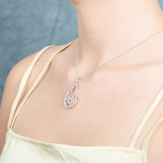 The picture shows a model wearing a 925 sterling silver pavé white gold vermeil nautilus shell pendant with topaz.