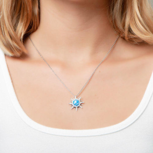 In this photo there is a model with blonde hair and a white shirt, wearing a sterling silver sun pendant with topaz and blue opalite gemstones.