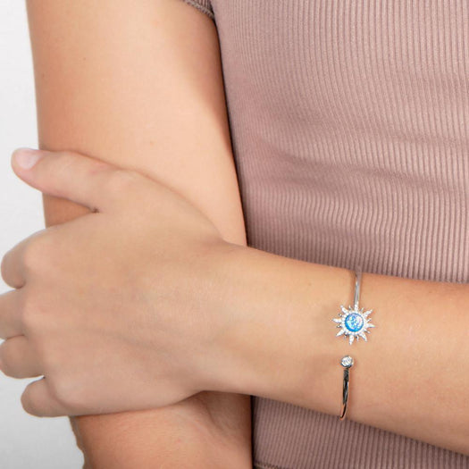 In this photo there is a model wearing a 925 sterling silver sun bangle with topaz, aquamarine, and blue opalite gemstones