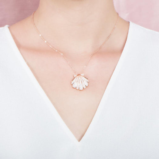 The picture shows a model wearing a 925 sterling silver, rose gold-vermeil, pavé oyster shell pendant with topaz.