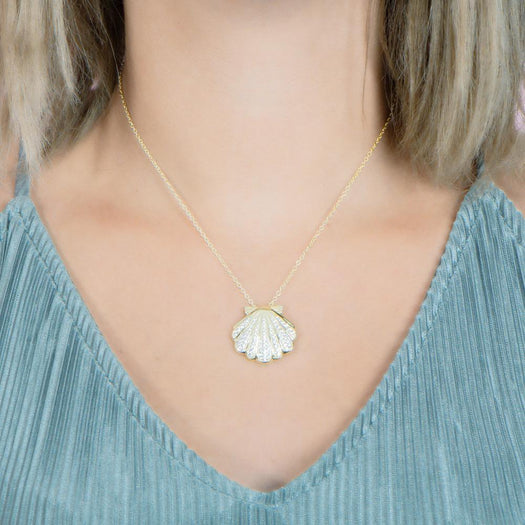 The picture shows a model wearing a 925 sterling silver, yellow gold-vermeil, pavé oyster shell pendant with topaz.