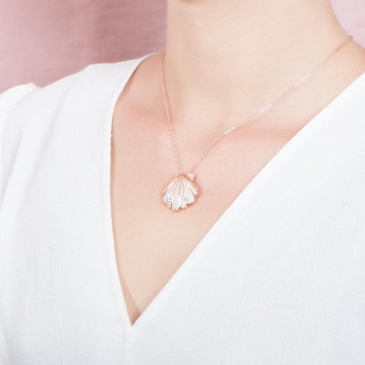 The picture shows a model wearing a 925 sterling silver, rose gold-vermeil, pavé oyster shell pendant with topaz.