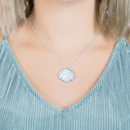 The picture shows a model wearing a 925 sterling silver, white gold-vermeil, pavé oyster shell pendant with topaz.