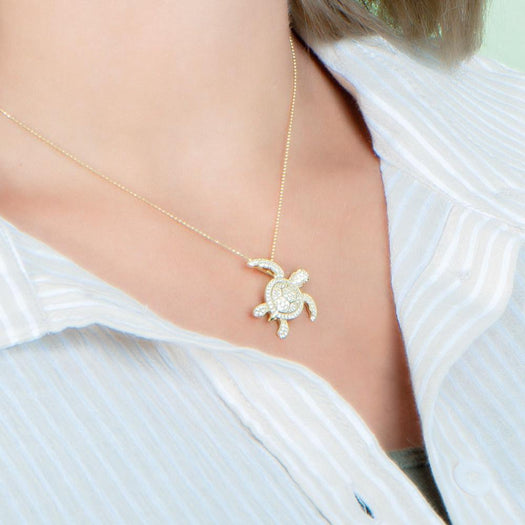 The picture shows a model wearing a 925 sterling silver yellow gold vermeil sea turtle pendant with cubic zirconia.
