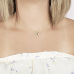 In this photo there is a model with blonde hair and a white shirt with flowers, wearing a yellow gold palm tree pendant with topaz gemstones.