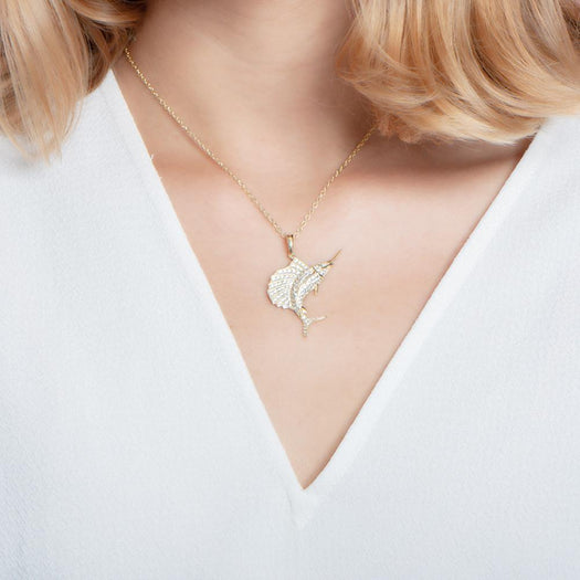 The picture shows a model wearing a 925 sterling silver, yellow gold vermeil, sailfish pendant with topaz.