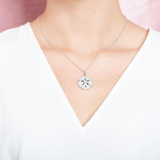 The picture shows a model wearing a medium 925 sterling silver, white gold vermeil, pavé sand dollar pendant with topaz.