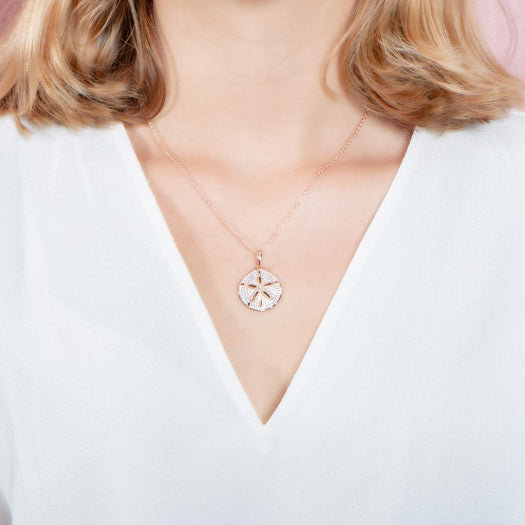 The picture shows a model wearing a medium 925 sterling silver, rose gold vermeil, pavé sand dollar pendant with topaz.