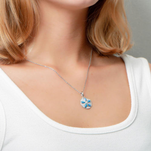 The picture shows a model wearing a 925 sterling silver pavé sand dollar pendant with opalite and topaz.