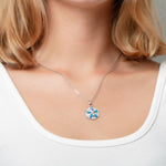 The picture shows a model wearing a 925 sterling silver pavé sand dollar pendant with opalite and topaz.